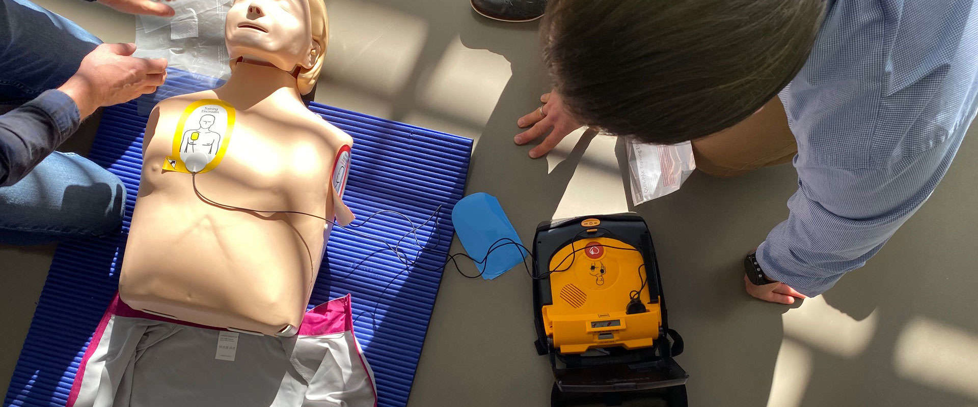 two people trying out defibrillator on the floor