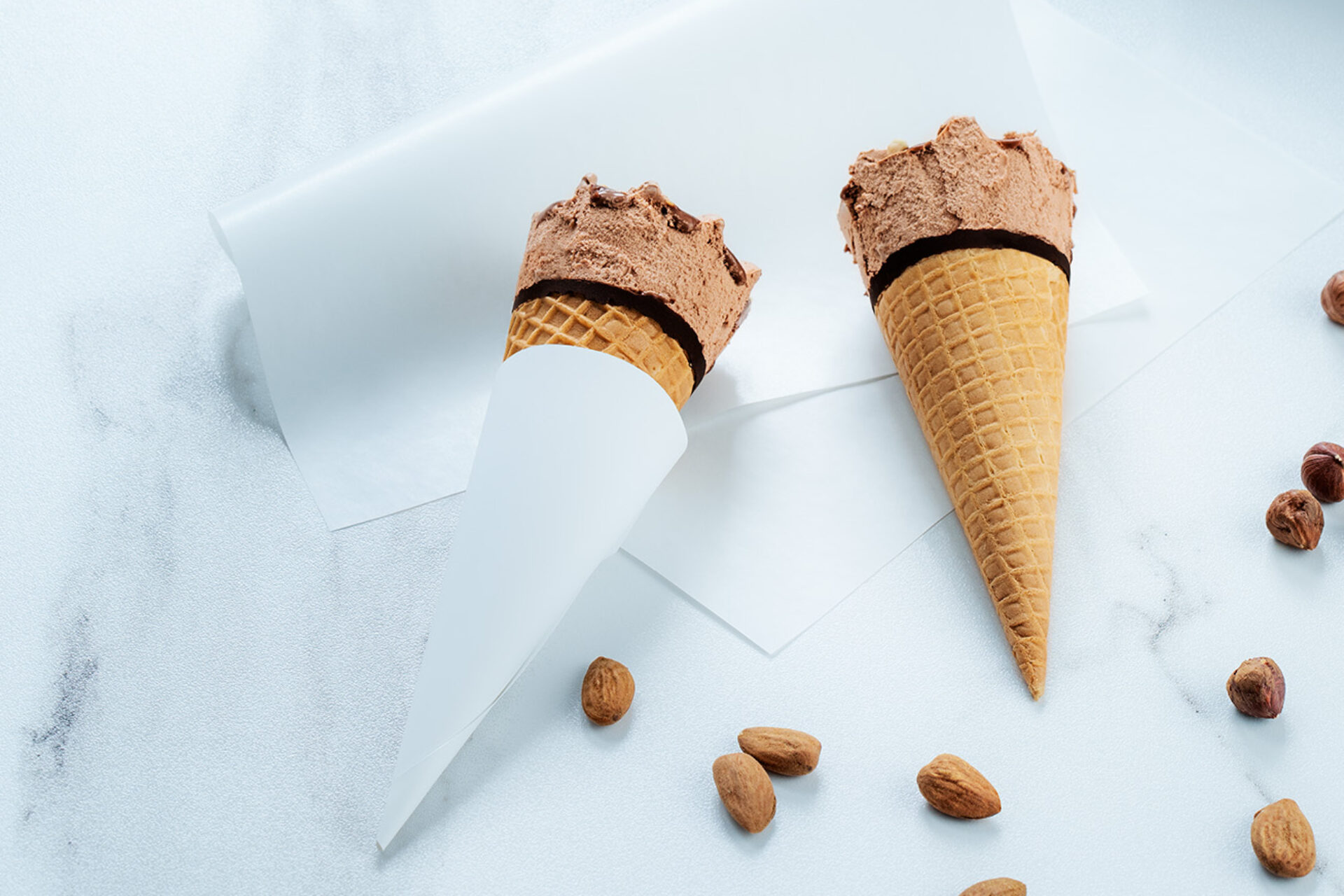 two cones of icecream packed in delfort paper are lying on a table